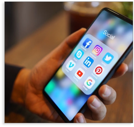 hand holding a phone with a folder of social media icon apps