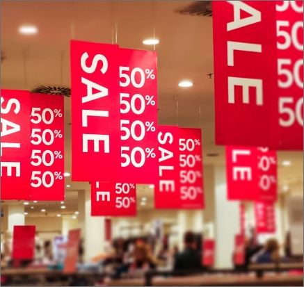 Red 50% off sales banners hanging from a ceiling with unfocused store in the background